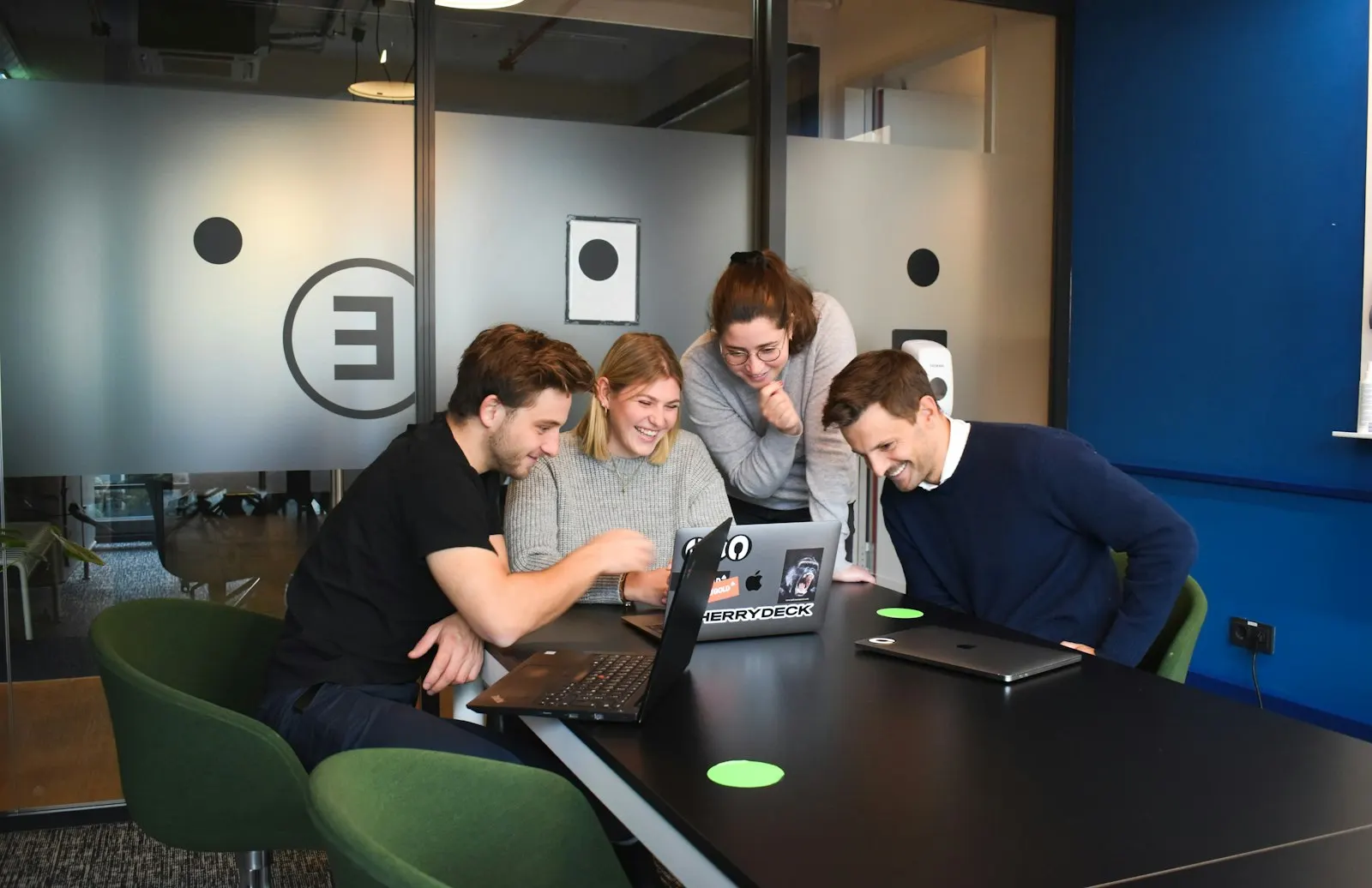 A small team reviewing work together on laptops in a meeting room