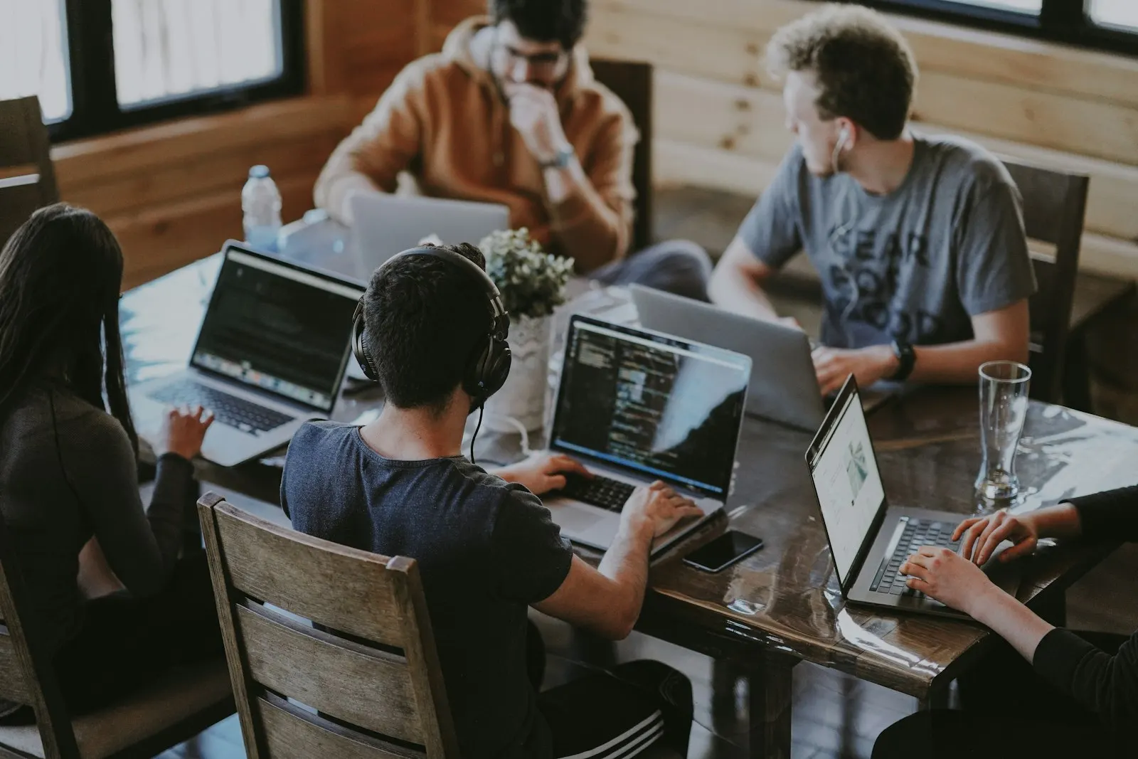 Software developers collaborating around a shared table with laptops